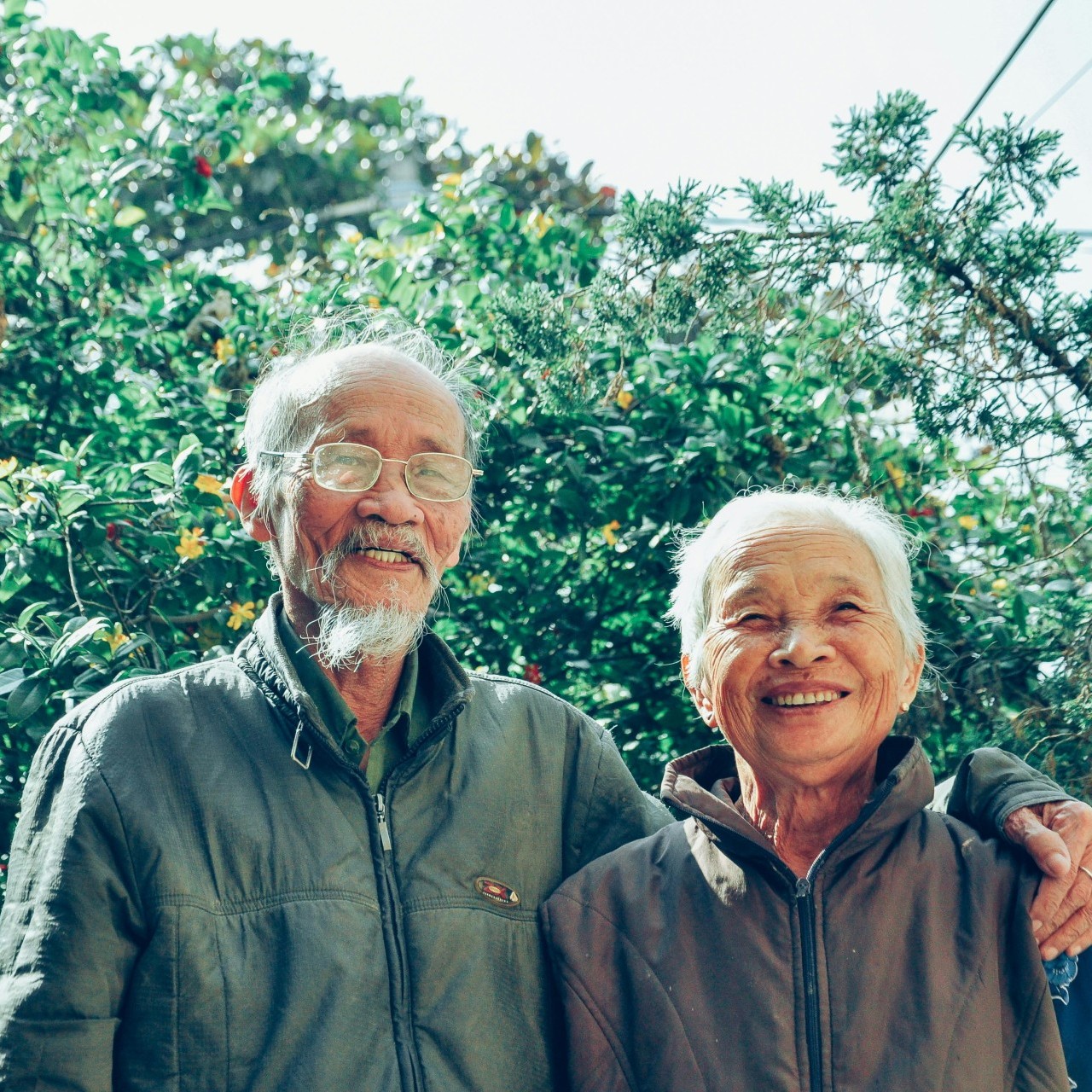 Small picture of an elderly couple standing in front of trees